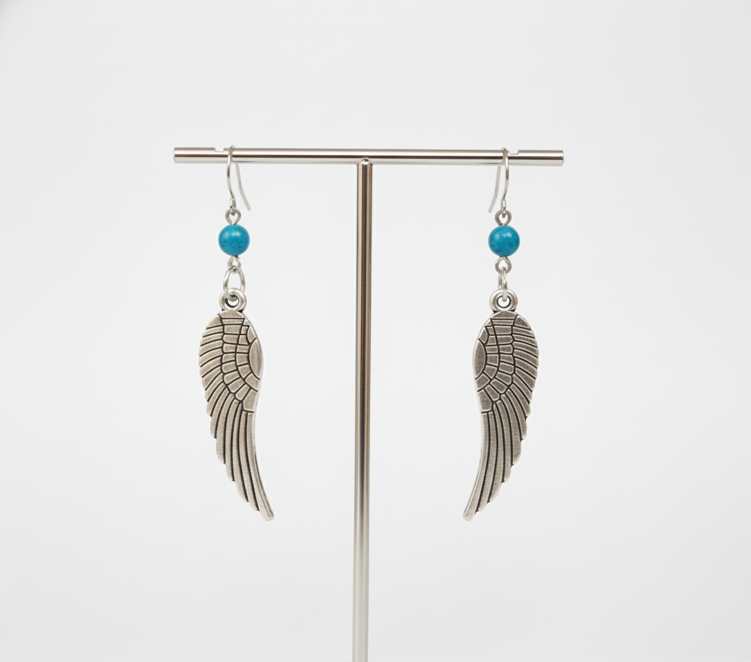 Pendientes largos con adorno en forma de alas y bolas color turquesa. Los pendientes son muy románticos con su adorno de alas de ángel, llevan cierre de mariposa a presión.