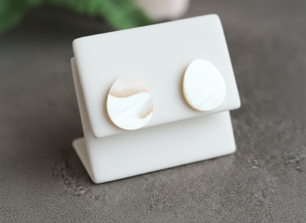 Pendientes tipo botón de nácar natural, son pequeños y discretos con forma de gota o lagrima, son naturales y por lo tanto no son exactamente iguales en&nbsp; color, cualquier diferencia entre ellas no es un fallo es la demostración de que son totalmente naturales.