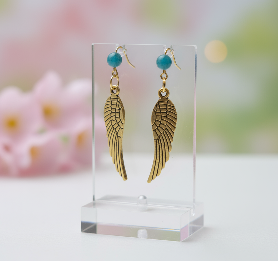 Pendientes largos con adorno en forma de alas y bolas color turquesa. Los pendientes son muy románticos con su adorno de alas de ángel, llevan cierre de mariposa a presión.